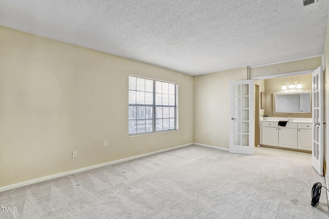 unfurnished room featuring light colored carpet, french doors, and a textured ceiling