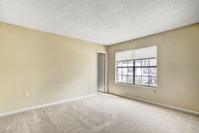 empty room with light colored carpet and a textured ceiling