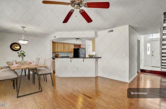 interior space featuring fridge, dark countertops, a ceiling fan, a peninsula, and visible vents
