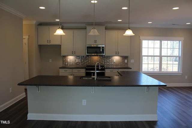 kitchen featuring a kitchen island with sink, sink, crown molding, and hanging light fixtures