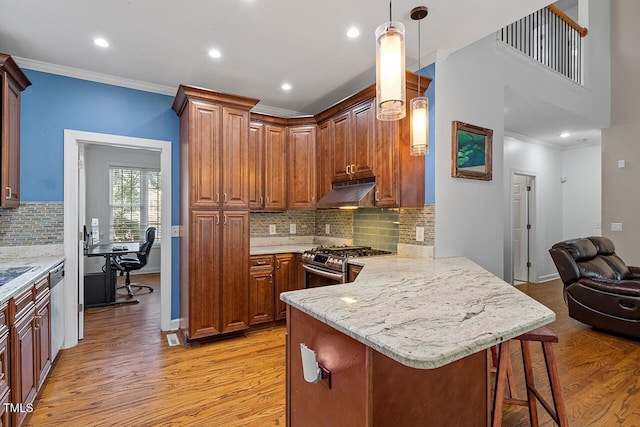 kitchen featuring a kitchen bar, hanging light fixtures, ornamental molding, appliances with stainless steel finishes, and kitchen peninsula