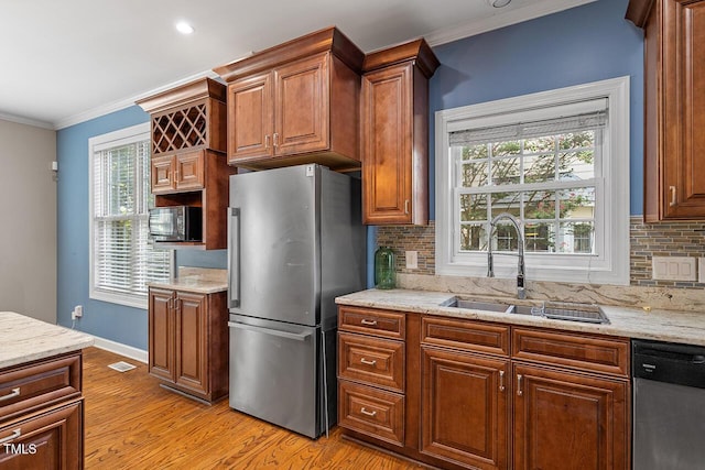 kitchen featuring sink, ornamental molding, light hardwood / wood-style floors, stainless steel appliances, and light stone countertops