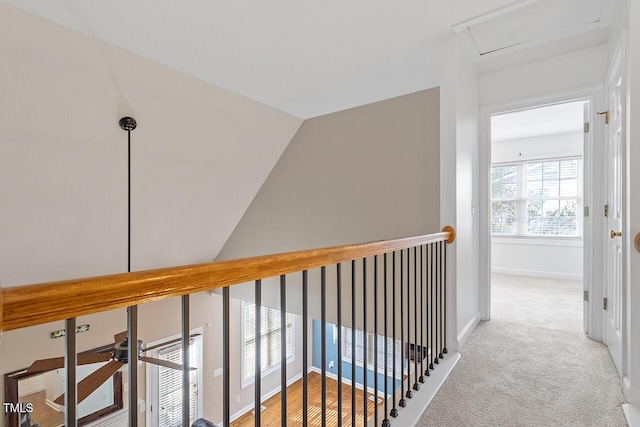 hall with lofted ceiling and light carpet