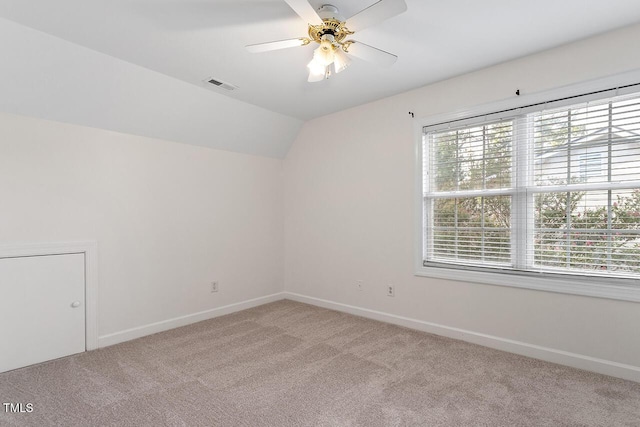 carpeted spare room featuring vaulted ceiling and ceiling fan