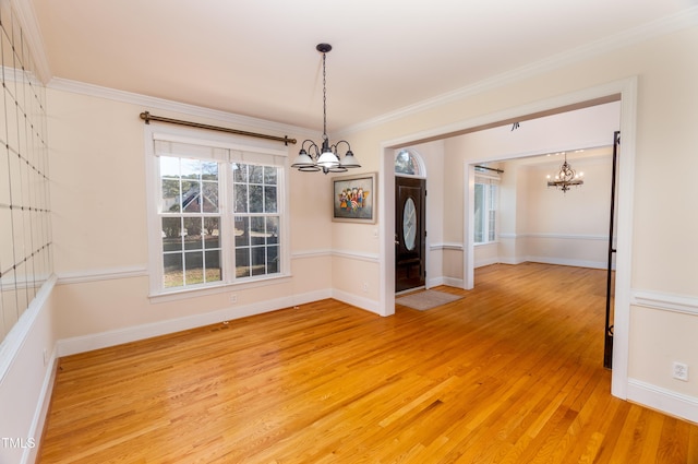 unfurnished dining area with a notable chandelier, ornamental molding, and hardwood / wood-style floors