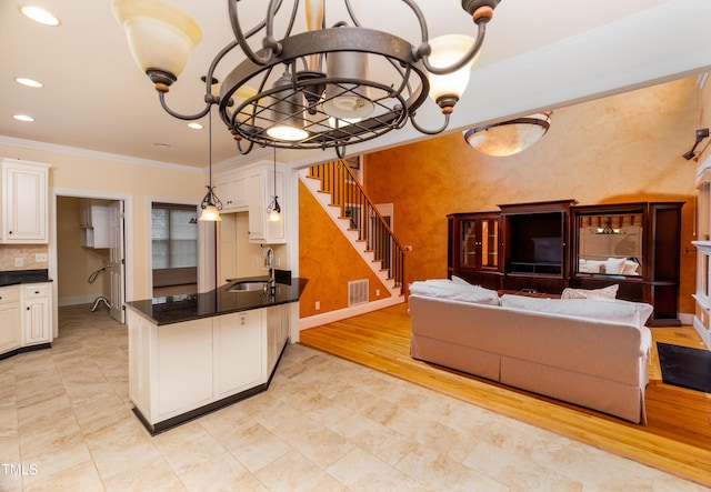 living room featuring an inviting chandelier, sink, crown molding, and light hardwood / wood-style floors