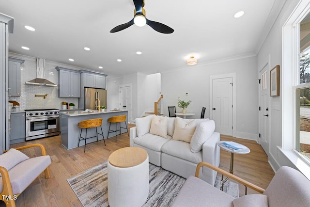 living room with crown molding, ceiling fan, and light hardwood / wood-style flooring