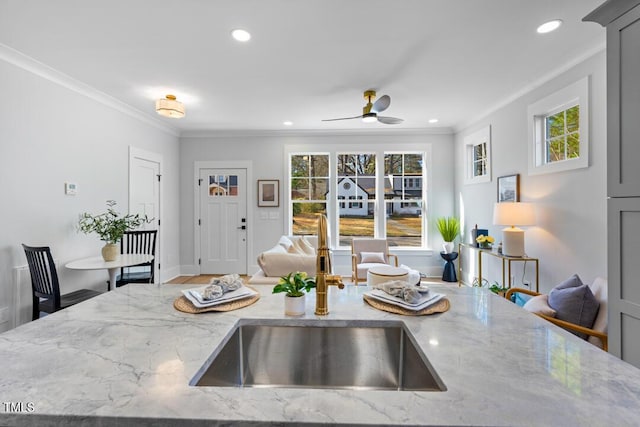 kitchen featuring sink, gray cabinetry, ornamental molding, ceiling fan, and light stone counters