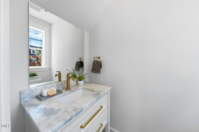 bathroom with vanity, lofted ceiling, and toilet