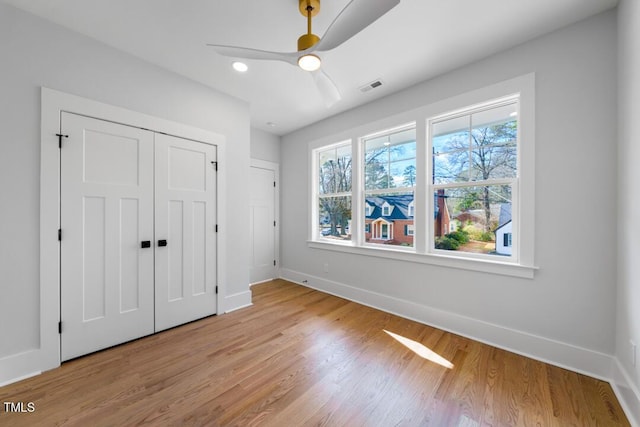 unfurnished bedroom with light hardwood / wood-style flooring, a closet, and ceiling fan