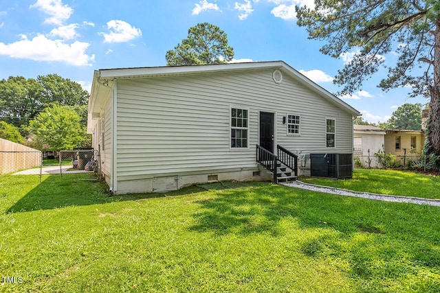 back of house featuring central AC unit and a yard