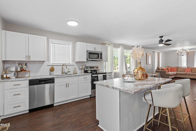 kitchen with sink, white cabinetry, dark hardwood / wood-style floors, stainless steel appliances, and light stone countertops