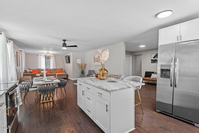 kitchen featuring a breakfast bar area, dark hardwood / wood-style floors, light stone counters, white cabinets, and stainless steel fridge with ice dispenser