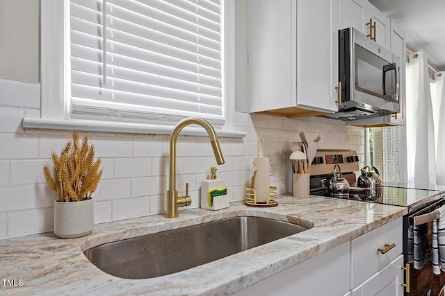 kitchen featuring white cabinetry, sink, stainless steel appliances, and light stone countertops