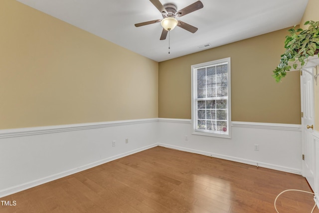 spare room featuring visible vents, baseboards, a ceiling fan, and wood finished floors