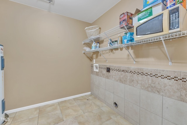 clothes washing area with light tile patterned floors, laundry area, baseboards, and washer hookup