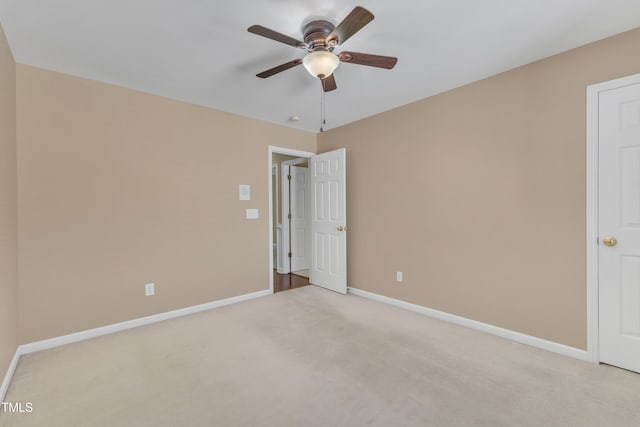 carpeted spare room featuring baseboards and a ceiling fan