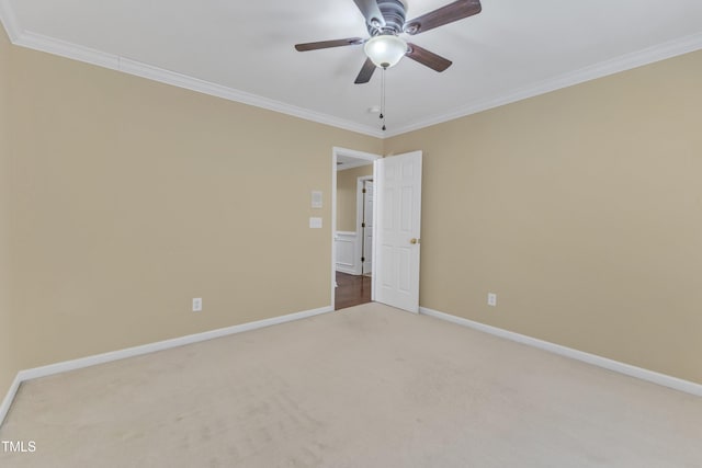 carpeted empty room featuring a ceiling fan, baseboards, and ornamental molding