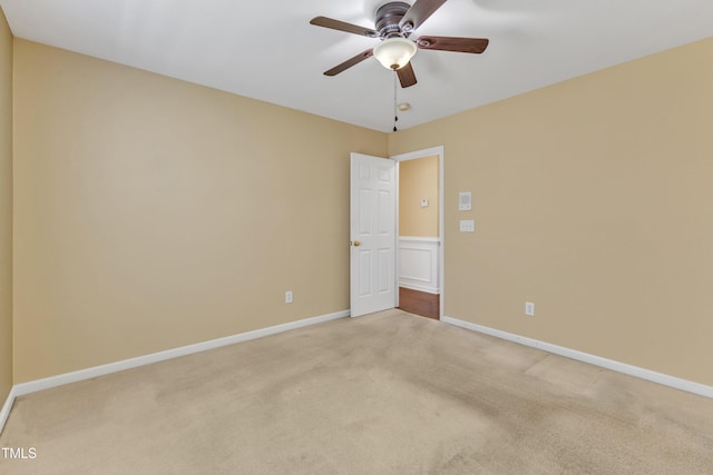 spare room with baseboards, light colored carpet, and a ceiling fan