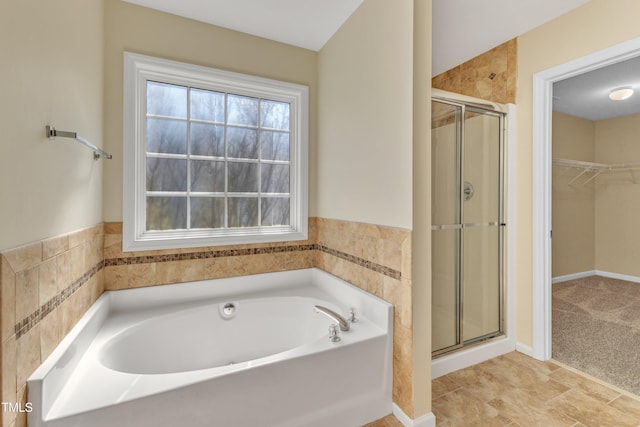 bathroom featuring a walk in closet, a shower stall, and a bath