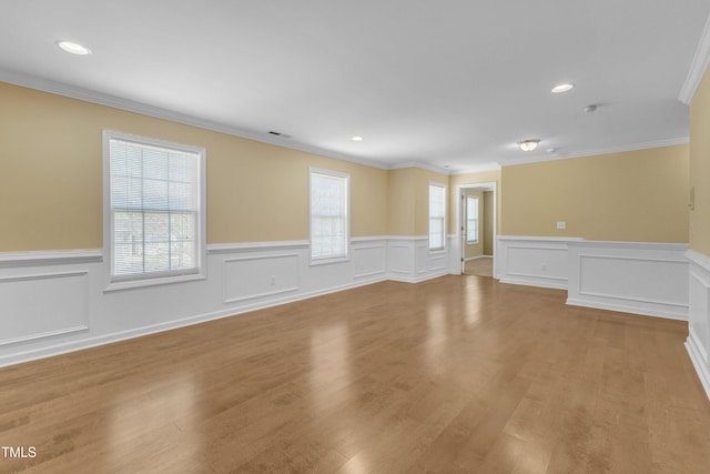 empty room featuring plenty of natural light, crown molding, and wood finished floors