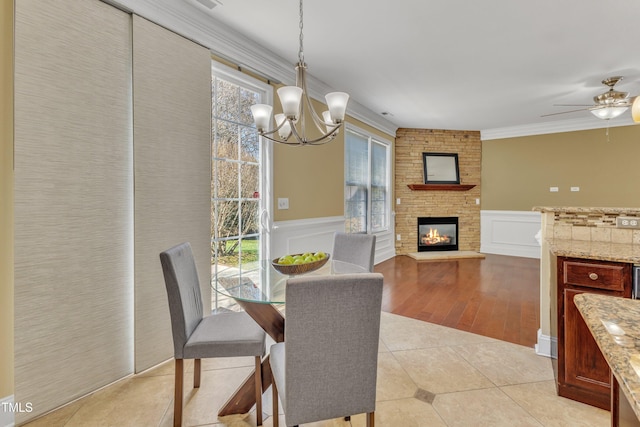 dining space with light tile patterned floors, a multi sided fireplace, a healthy amount of sunlight, and crown molding