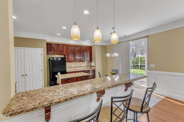 kitchen with a wainscoted wall, a center island, freestanding refrigerator, crown molding, and decorative backsplash