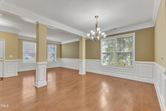 unfurnished dining area featuring crown molding, decorative columns, wood finished floors, and a chandelier