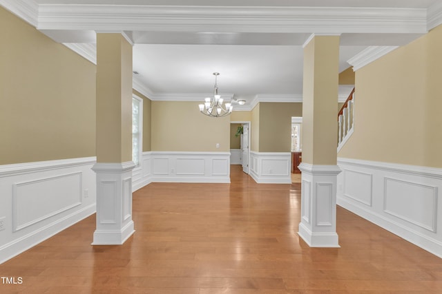 unfurnished dining area featuring light wood-type flooring, an inviting chandelier, crown molding, and stairway