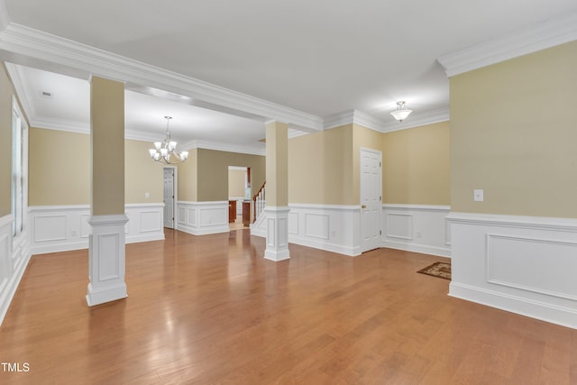 unfurnished room featuring wood finished floors, a chandelier, stairs, and crown molding