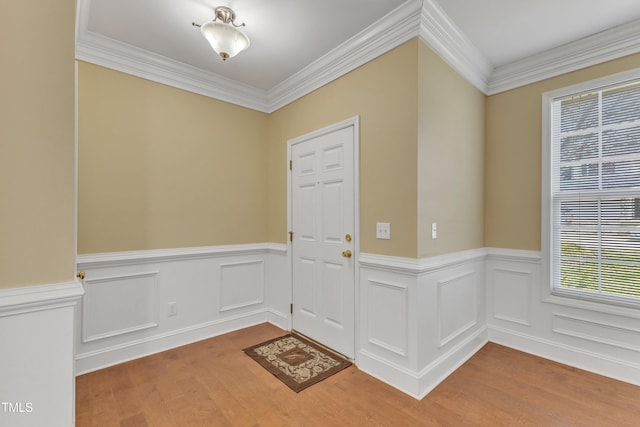 entryway with wainscoting, crown molding, and wood finished floors