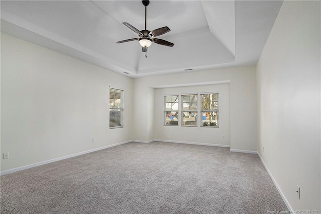 unfurnished room featuring a tray ceiling, ceiling fan, and carpet