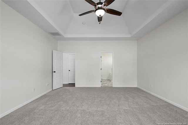 unfurnished bedroom with ceiling fan, a raised ceiling, and light carpet