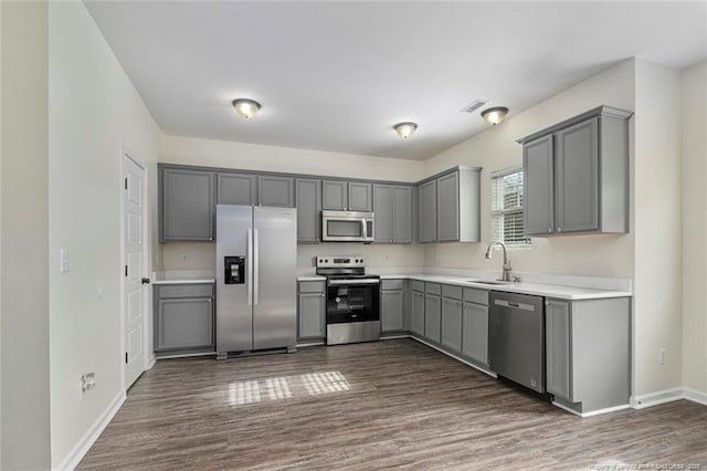 kitchen with gray cabinets, appliances with stainless steel finishes, sink, and dark wood-type flooring