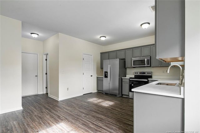 kitchen with appliances with stainless steel finishes, dark hardwood / wood-style flooring, gray cabinets, and sink