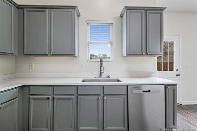 kitchen with gray cabinets, wood-type flooring, sink, and stainless steel dishwasher