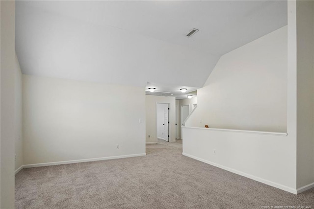 spare room featuring light carpet and vaulted ceiling