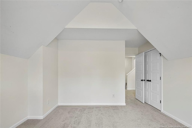 additional living space featuring vaulted ceiling and light colored carpet