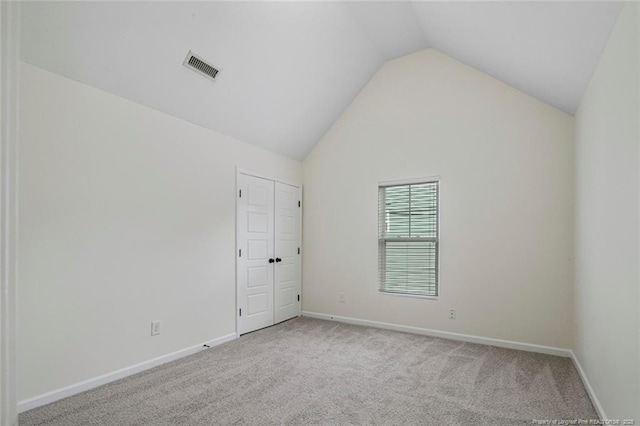 carpeted empty room featuring high vaulted ceiling