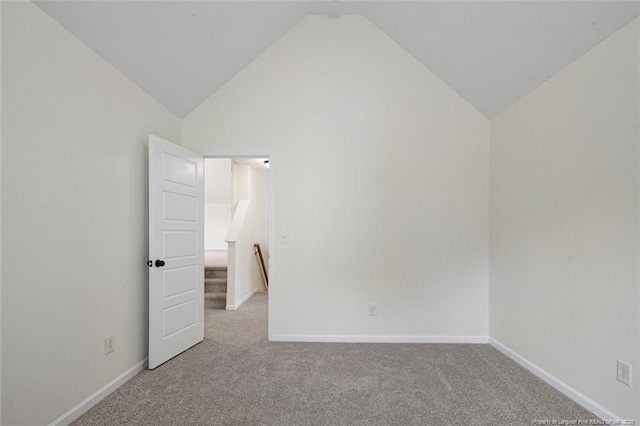 carpeted spare room with vaulted ceiling