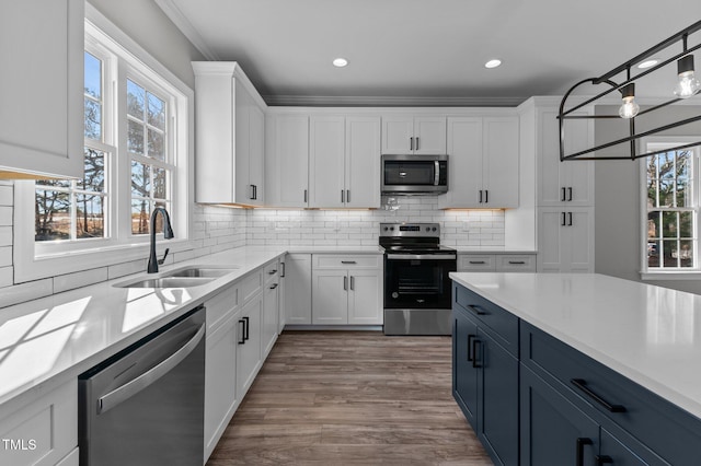 kitchen featuring blue cabinetry, sink, white cabinetry, pendant lighting, and stainless steel appliances