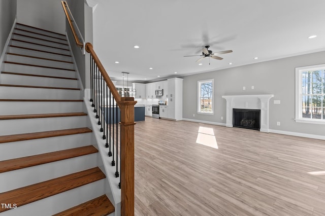 unfurnished living room with crown molding, a wealth of natural light, and light wood-type flooring