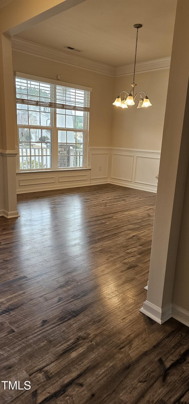 empty room with a healthy amount of sunlight, ornamental molding, and a chandelier