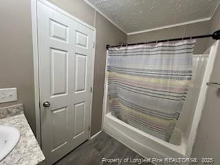 bathroom with a textured ceiling, ornamental molding, vanity, shower / bath combo with shower curtain, and hardwood / wood-style flooring