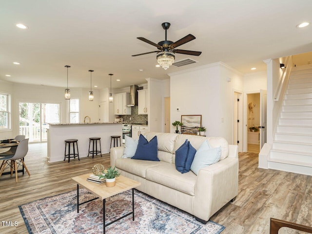 living room featuring crown molding, sink, ceiling fan, and light hardwood / wood-style floors