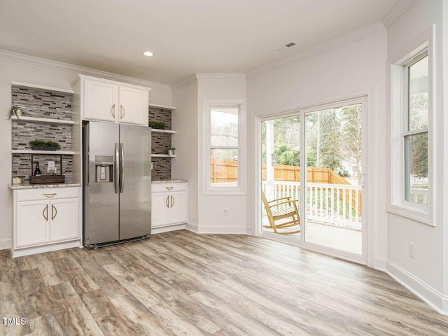 kitchen featuring light stone counters, stainless steel fridge with ice dispenser, light wood-type flooring, ornamental molding, and white cabinets