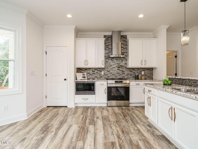 kitchen with pendant lighting, built in microwave, white cabinets, stainless steel range, and wall chimney exhaust hood