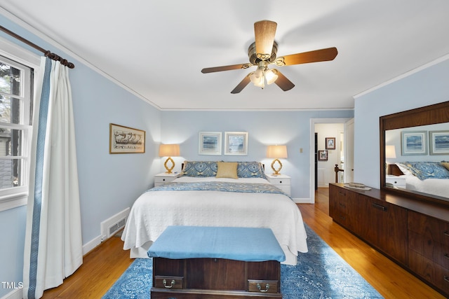 bedroom with crown molding, light hardwood / wood-style floors, and ceiling fan