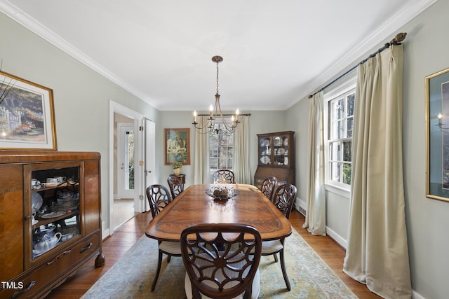 dining space featuring crown molding, wood-type flooring, and a chandelier