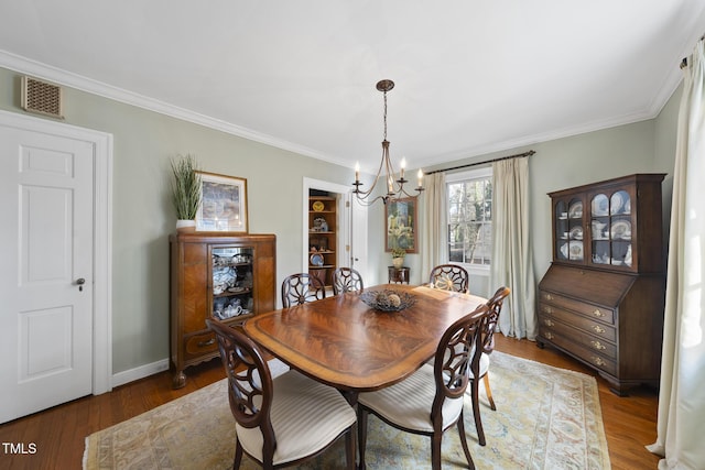 dining space featuring wood-type flooring, ornamental molding, and a chandelier